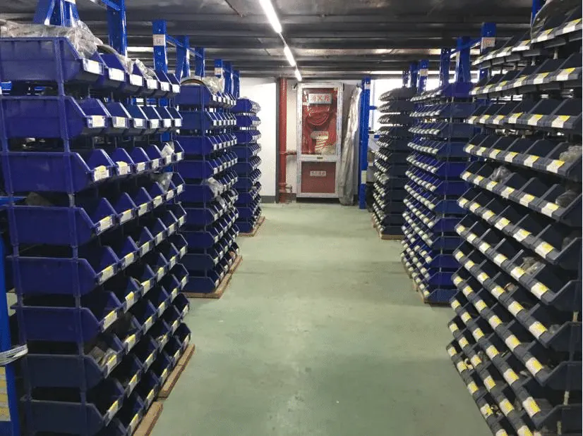 Labelled small-parts bins lining a warehouse aisle